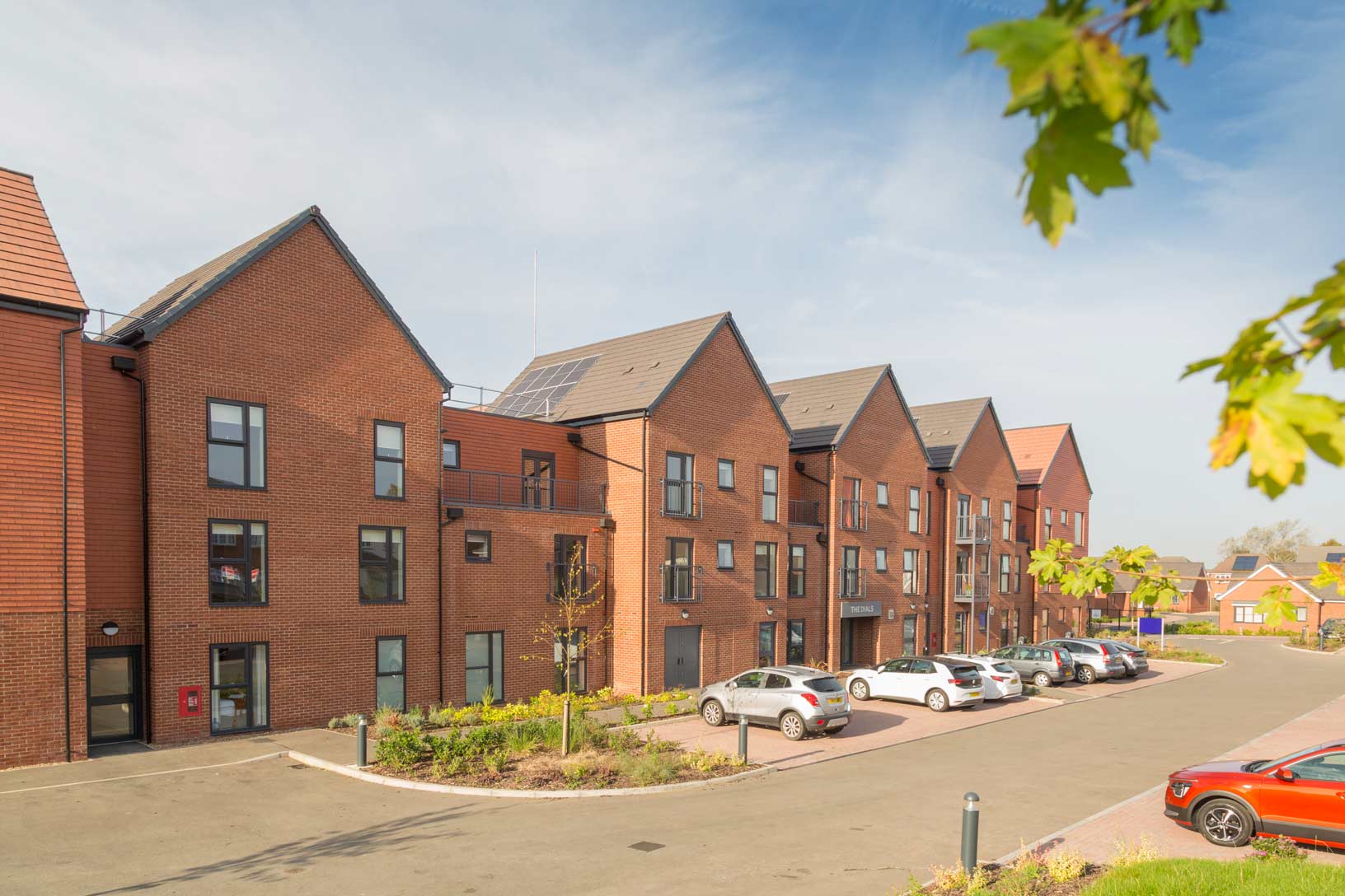 A red brick apartment duplex with a car park in front for easy access.
