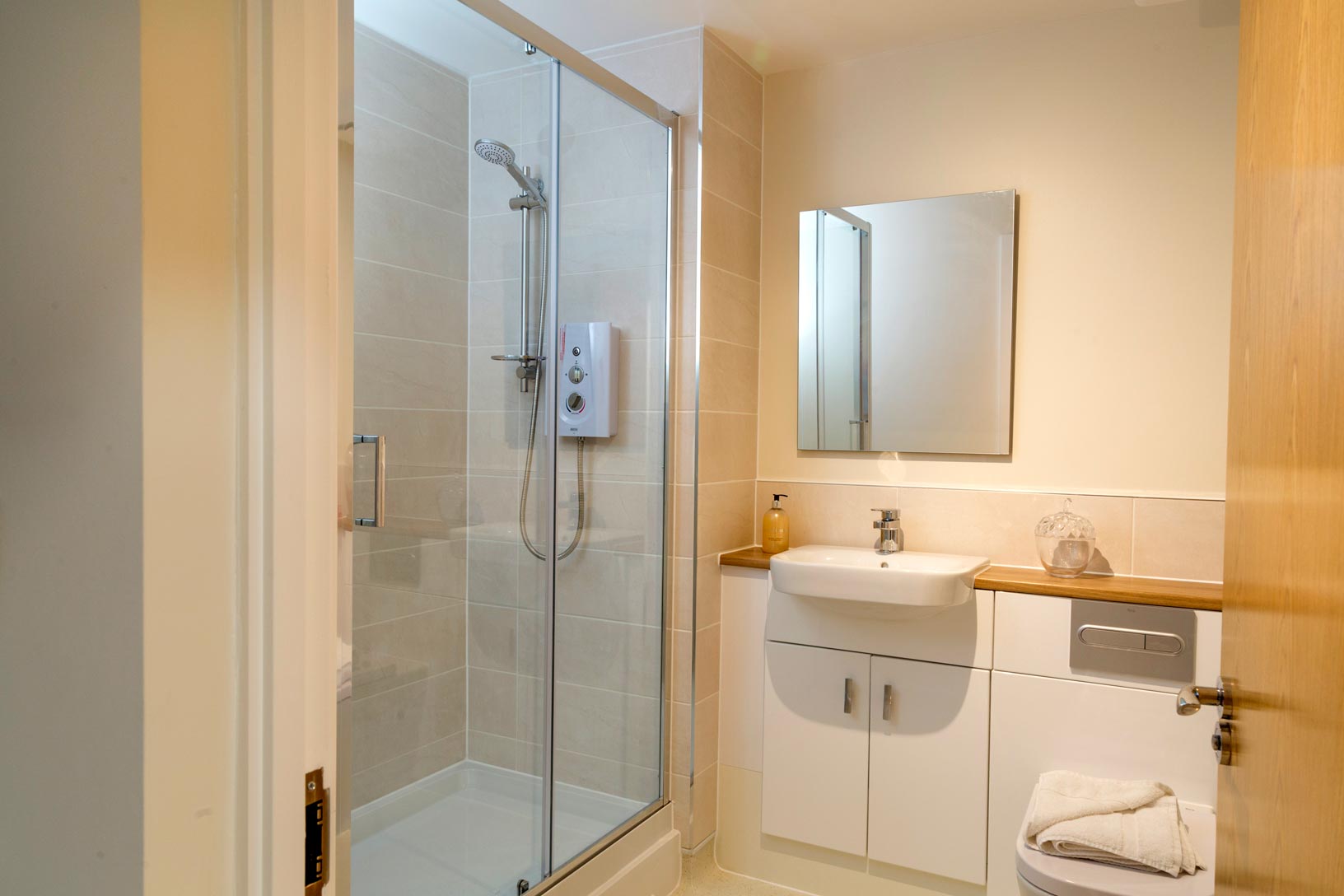 A shower room facilitated with modern mirror, shower head and basin with storage accessibility.