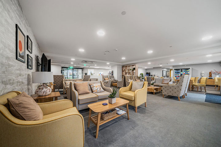 A spacious communal living room adorned with vibrant yellow chairs and tables.