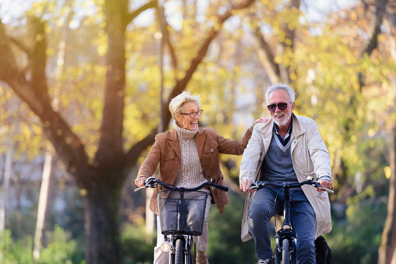 An elderly couple enjoying a bike ride together in a serene park setting. Nearby their apartment at the The Dials.